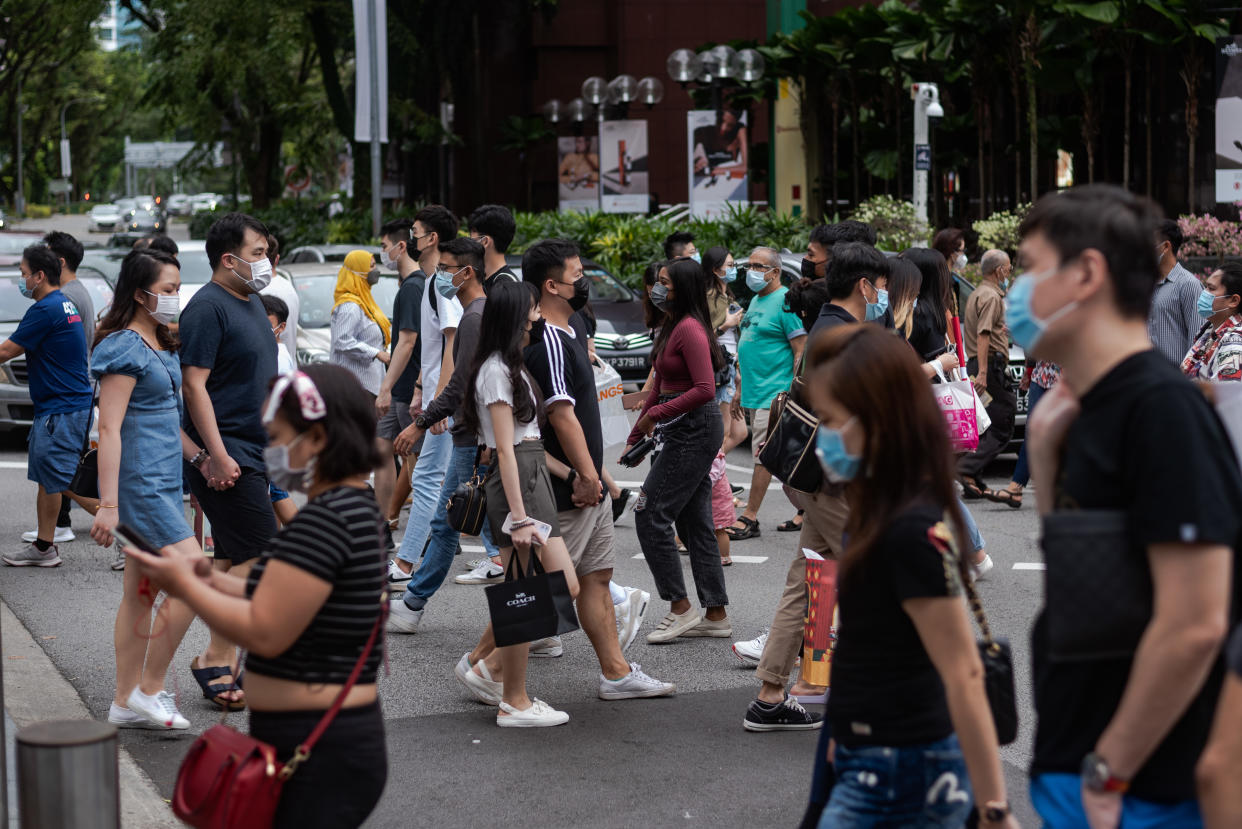 Crowds of people wearing protective face masks walk in Singapore's Orchard Road shopping district on Sunday, 12 December 2021. Singapore authorities reported on 15 December 2021, 2 persons with the Omincron variant of the Covid-19 virus who dined in restaurants along Orchard Road. (Photo by Joseph Nair/NurPhoto via Getty Images)