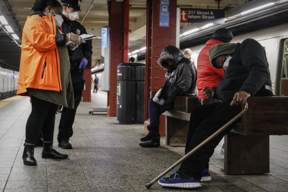 FILE - A homeless outreach worker and New York police officer assist passengers found sleeping on subway cars at the 207th Street A-train station, Thursday, April 30, 2020, in the Manhattan borough of New York. In New York City's latest effort to address a mental health crisis on its streets and subways, Mayor Eric Adams announced Tuesday, Nov. 29, 2022, that authorities would more aggressively intervene to help people in need of treatment, saying there was "a moral obligation" to do so, even if it means providing care to those who don't ask for it. (AP Photo/John Minchillo, File)