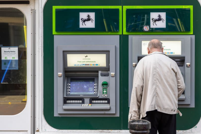 A man withdrawing money from the ATM outside Lloyds Bank