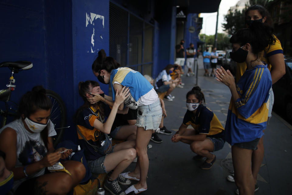 Hinchas acongojados frente a un afiche de Diego Maradona en la entrada de La Bombonera, el estadio del club Boca Juniors, en Buenos Aires, el miércoles 25 de noviembre de 2020. Tenía 60 años. (AP Foto/Natacha Pisarenko)