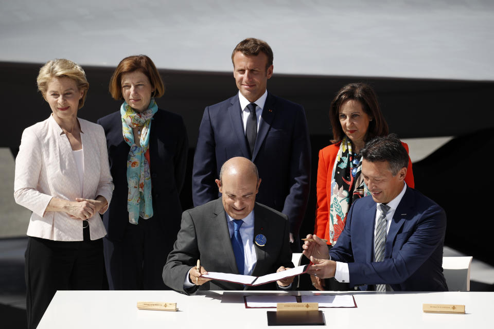 French President Emmanuel Macron, German Defense Minister Ursula von der Leyen, left, French Defense Minister Florence Parly, second left, and Spanish Defense Minister Margarita Robles, right, watch Airbus Defense and Space Chief Executive Officer Dirk Hoke (down right) and Dassault Aviation Chairman and CEO Eric Trappier during a signature ceremony as part as the unveiling of the French-German-Spanish new generation fighter model during Le Bourget Airport near Paris, France, Monday June 17, 2019. (Yoan Valat/Pool via AP)