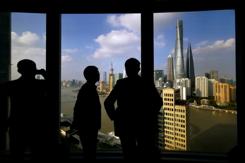 FILE PHOTO: People stand near a window overlooking the financial district in Shanghai