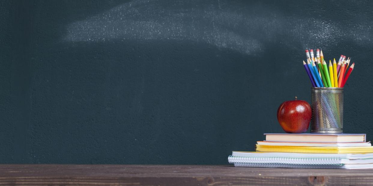 pencil tray and an apple on notebooks on school teacher's desk