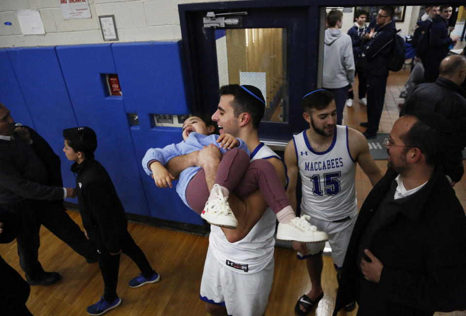 Guard Simcha Halpert lifts Elian Tsaidi, 2, in the Yeshiva University gym in New York, Feb. 22, 2020. Halpert works in a basketball camp run by Tsaidi's father, a rabbi, in his hometown of Los Angeles. (AP Photo/Jessie Wardarski)