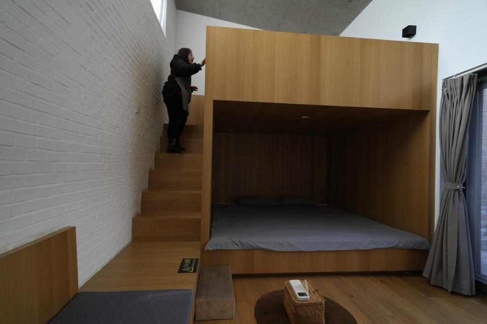 A local resident hired as a cleaner for a traditional courtyard house turned into lodging for tourists, inspects one of the rooms in Houheilong Miao, a village in Yanqing on the outskirts of Beijing, China, Wednesday, Jan. 5, 2022. The village has a view of the Olympics skiing venue in the distance. Its 20 mostly vacant traditional courtyard houses have been turned into lodgings and a cafe dubbed the "Winter Olympic Home." (AP Photo/Ng Han Guan)