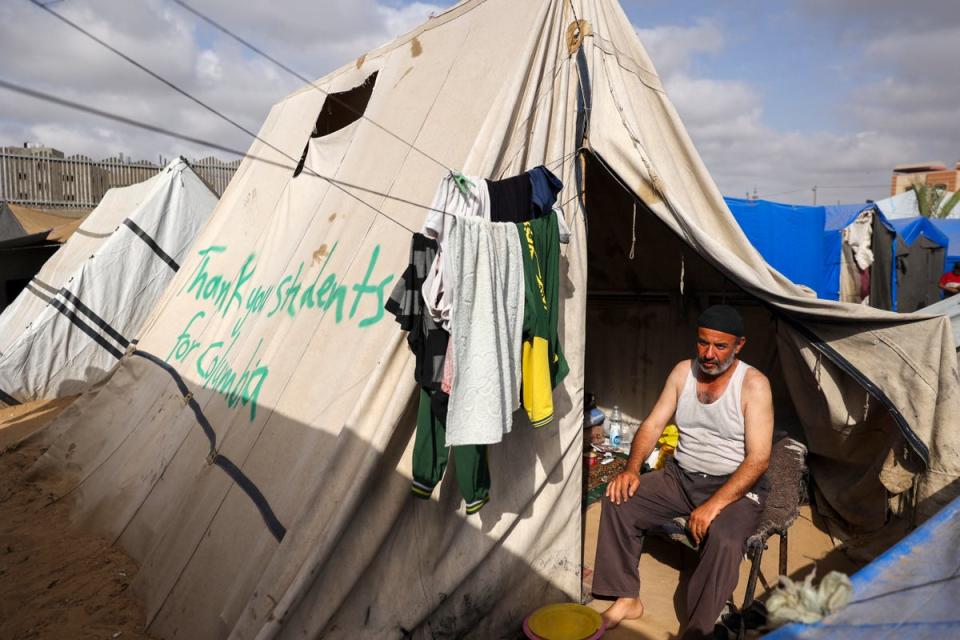 A man sits in Rafah in a tent with the message “thank you students for Columbia” painted on the side on 27 April. The New York Police Department has arrested hundreds of protesters at Columbia since their protests began on 17 April (AFP via Getty Images)