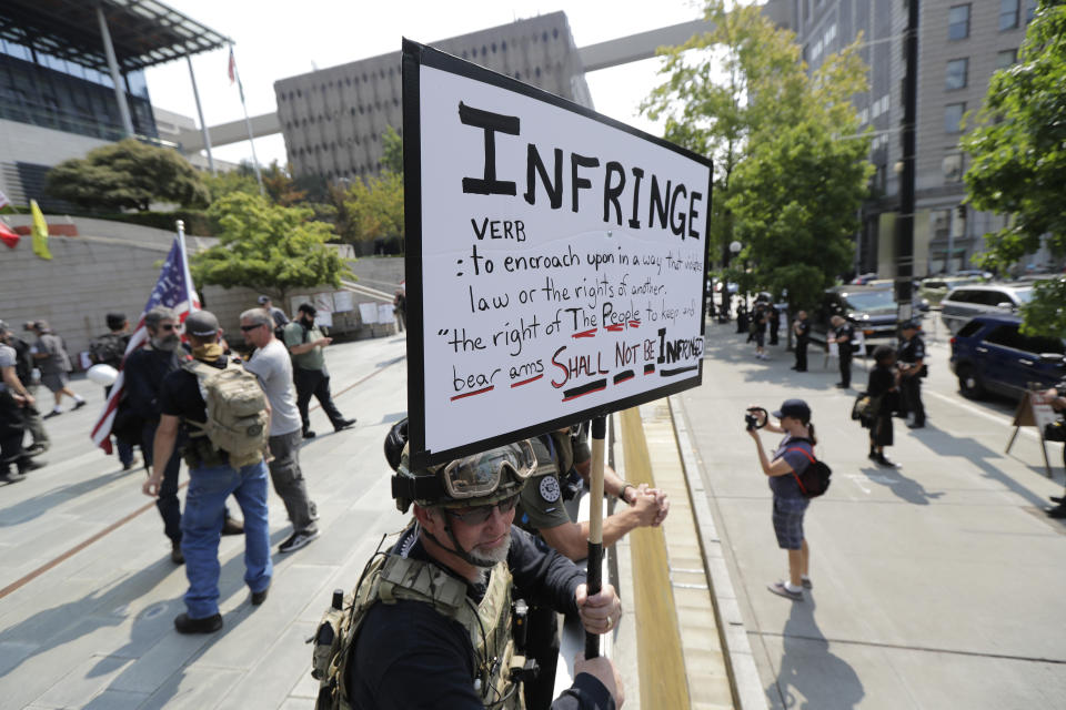 A protester stands on the side of the street with members of Patriot Prayer and other groups advocating for gun rights at a rally, Saturday, Aug. 18, 2018, at City Hall in Seattle. (AP Photo/Ted S. Warren)