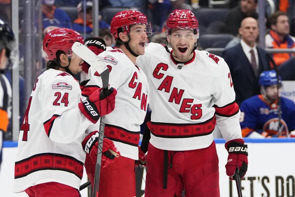 Carolina Hurricanes' Mackenzie MacEachern, center, celebrates with teammates Brett Pesce, right, and Seth Jarvis (24) after scoring a goal during the third period of Game 4 of an NHL hockey Stanley Cup first-round playoff series against the New York Islanders, Sunday, April 23, 2023, in Elmont, N.Y. The Hurricanes won 5-2. (AP Photo/Frank Franklin II)