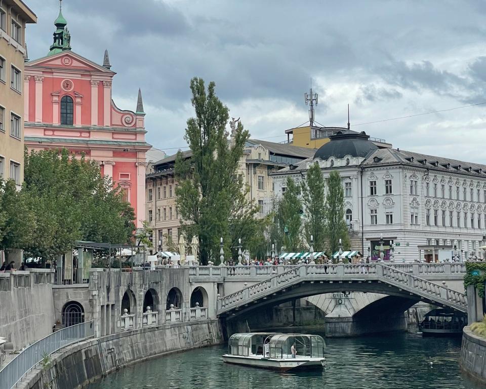 Buildings with ornate architecture near a canal with boats and a bridge.