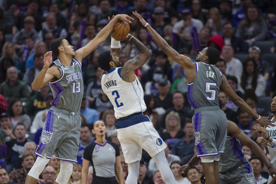 Dallas Mavericks guard Kyrie Irving (2) is guarded by Sacramento Kings' Keegan Murray (13) and De'Aaron Fox (5) during the second half of an NBA basketball game in Sacramento, Calif., Friday, Feb. 10, 2023. The Mavericks won 122-114. (AP Photo/Randall Benton)