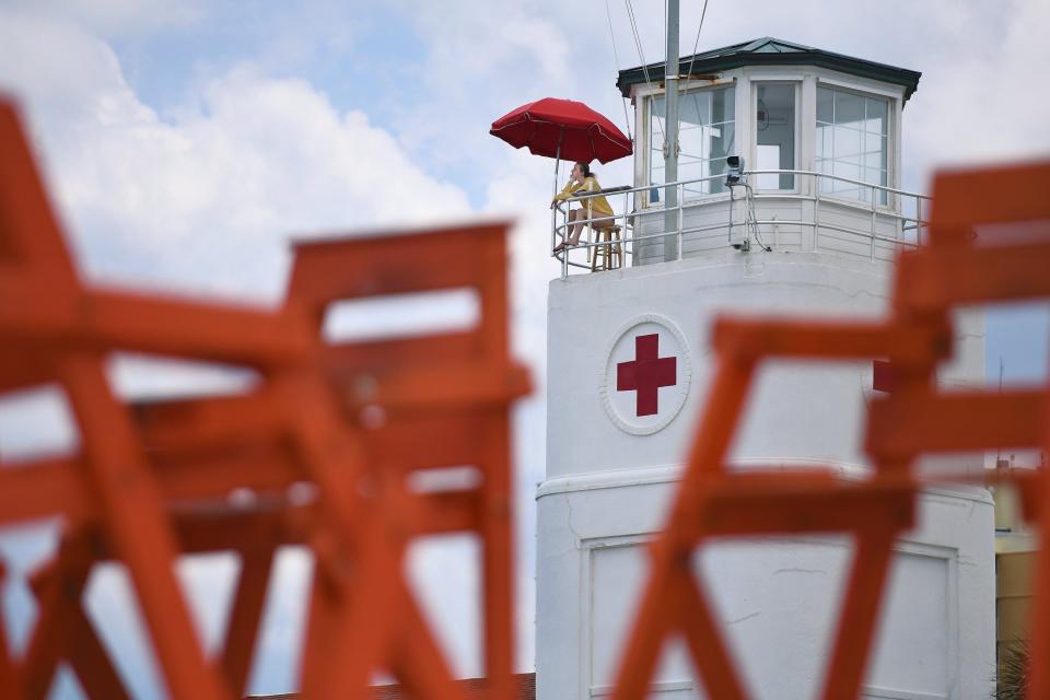 From the historic lifeguard station on the oceanfront, a lifeguard keeps an eye on the scattered beachgoers along Jacksonville Beach in May 2020.