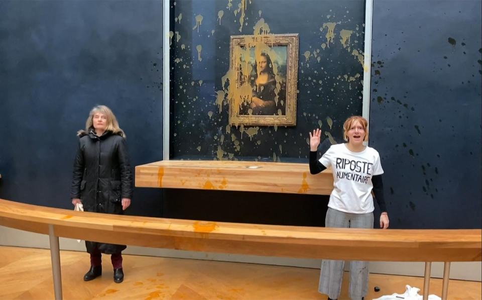 PHOTO: This image grab taken from AFPTV footage shows two environmental activists from the collective dubbed 'Riposte Alimentaire' gesturing as they stand in front of the 'Mona Lisa' painting at the Louvre museum in Paris, on Jan. 28, 2024.  (David Cantiniaux/AFPTV/AFP via Getty Images)