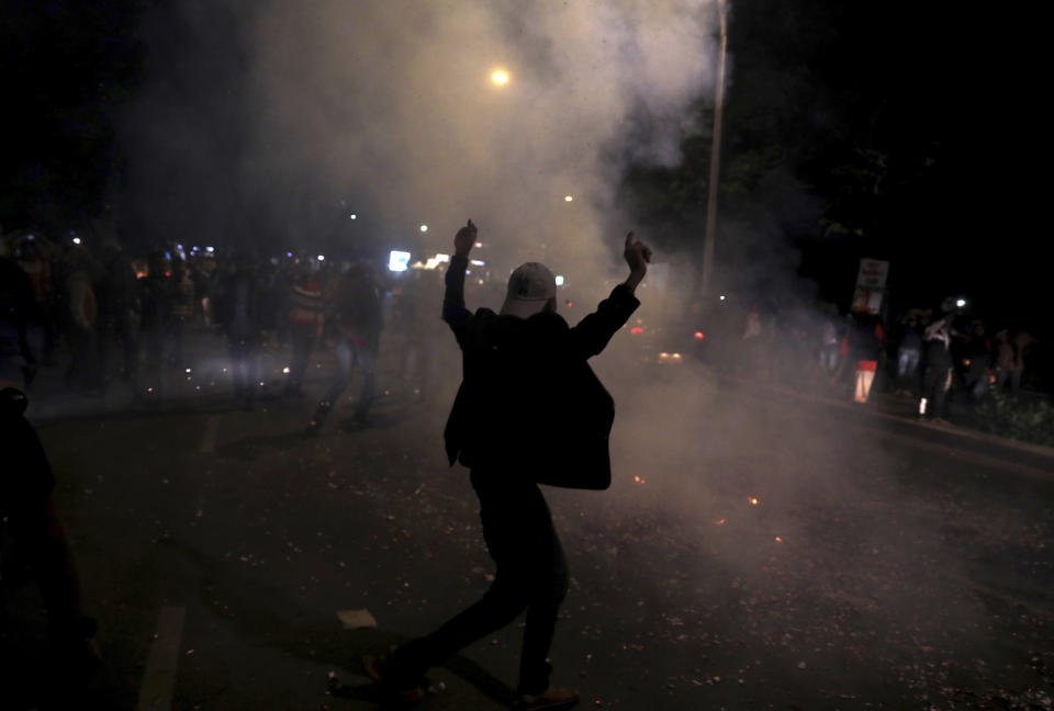 An Indian man shouts slogans silhouetted against smoke from bursting of crackers as he celebrates reports of Indian aircrafts bombing Pakistan territory, in New Delhi, India, Tuesday, Feb. 26, 2019. A pre-dawn airstrike inside Pakistan that India said targeted a terrorist training camp and killed a "very large number" of militants ratcheted up tensions on Tuesday between the two nuclear-armed rivals at odds over the disputed territory of Kashmir. (AP Photo/Altaf Qadri)