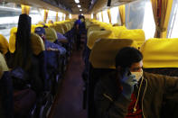 Christopher Bagay, right, a kitchen crew of the Aida Sol cruise ship in Europe, talks on his phone as he heads home together with other overseas Filipino workers on a government provided bus ride in Manila, Philippines Thursday, May 28, 2020. Bagay said it took him about two months to go through repetitive quarantines in Spain, Germany and Manila before he was finally allowed to go home. Tens of thousands of workers have returned by plane and ships as the pandemic, lockdowns and economic downturns decimated jobs worldwide in a major blow to the Philippines, a leading source of global labor. (AP Photo/Aaron Favila)