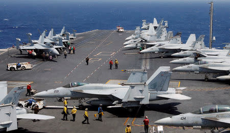 FILE PHOTO - U.S. Navy personnel prepare to launch an F18 fighter jet on the deck of USS Carl Vinson during a routine exercise in South China Sea, March 3, 2017. REUTERS/Erik De Castro/File Photo