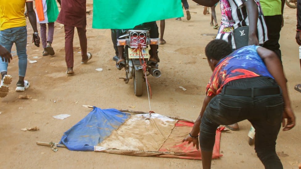 People drag a French flag on a motorbike on the streets of Niamey, Niger. Photo: August 2023