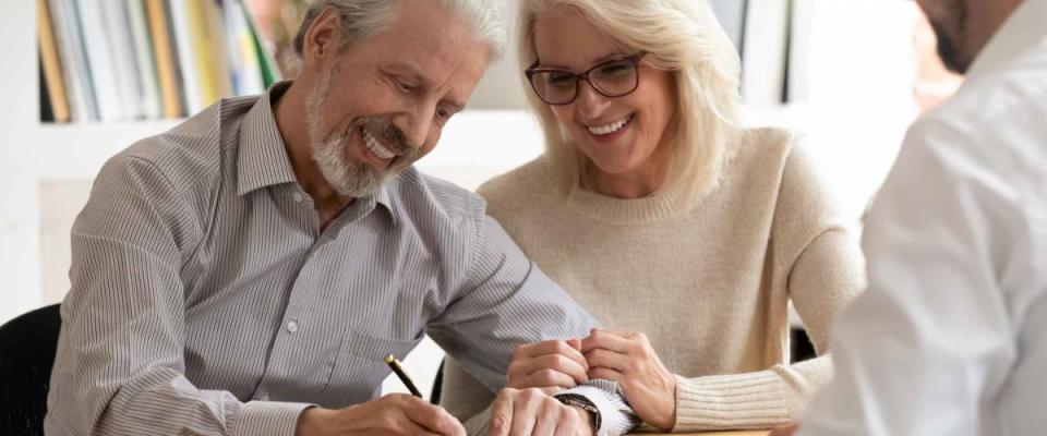 Happy older family couple sign document in office with younger man