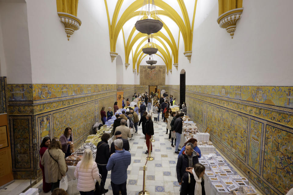 Customers browse marmalades and cakes made by cloistered nuns at a special market at the Reales Alcazares in Seville, Spain, on Tuesday, Dec. 5, 2023. It's the fortnight before Christmas and all through the world's Catholic convents, nuns and monks are extra busy preparing the traditional delicacies they sell to a loyal fan base even in rapidly secularizing countries. (AP Photo/Laura Leon)