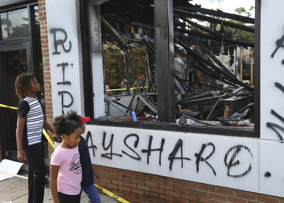 Children take in the burned Wendy's location in Atlanta on Monday, June 15, 2020, outside which Rayshard Brooks, a 27-year-old black man, was fatally shot by a white Atlanta police officer Friday night. (Curtis Compton/Atlanta Journal-Constitution via AP)