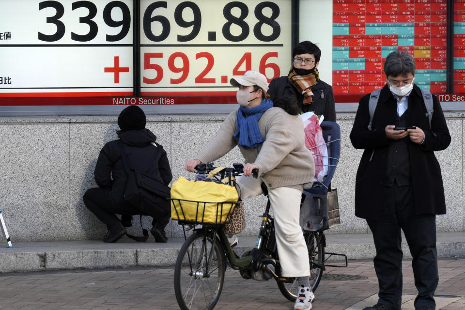 People wait for traffic signal at pedestrian crossing in front of an electronic stock board showing Japan's Nikkei 225 index at a securities firm Tuesday, Jan. 9, 2024, in Tokyo. (AP Photo/Eugene Hoshiko)