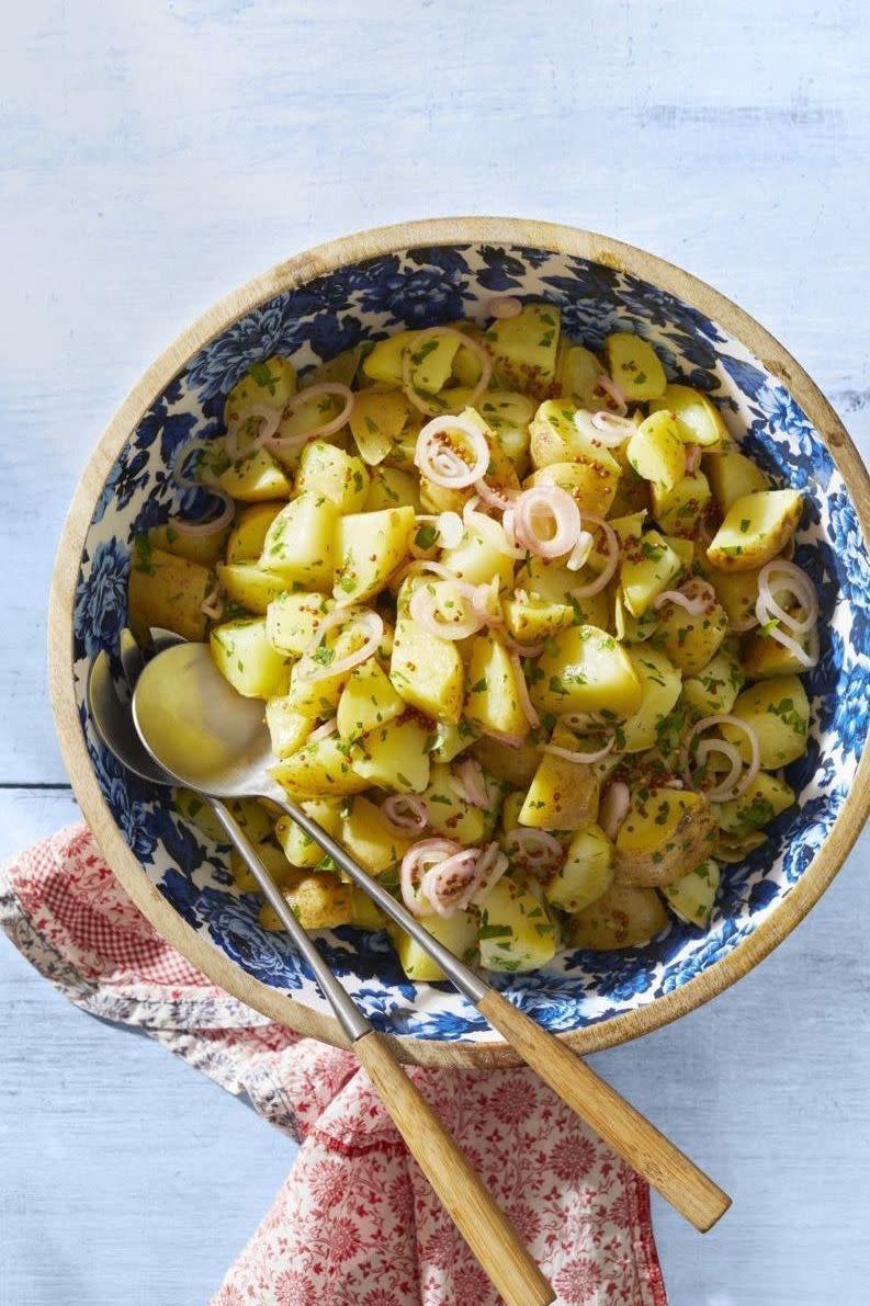 potato salad with mustard vinaigrette in blue bowl with serving spoons