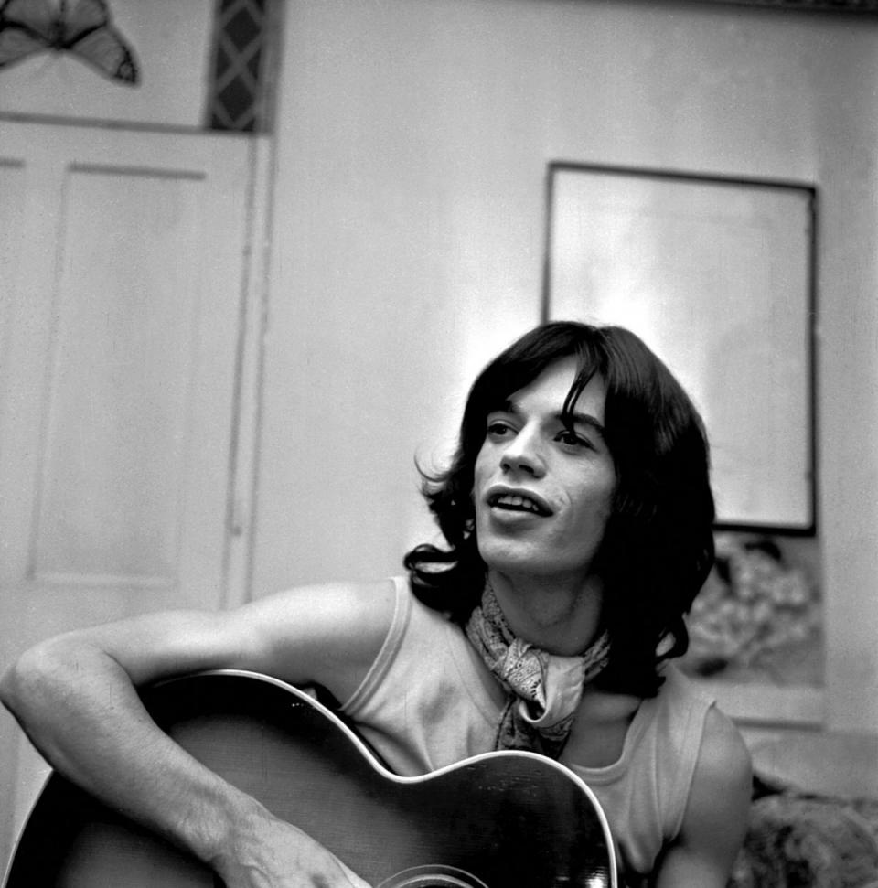 Rolling Stone Mick Jagger relaxes with a guitar in a London dressing room in 1968. (AP Photo/Bob Dear)