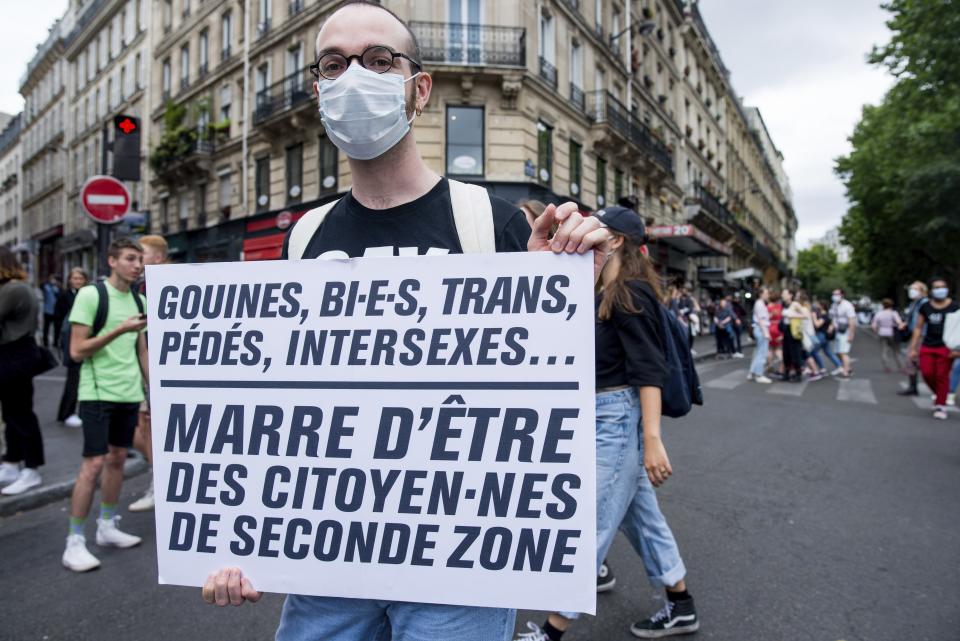 A young man arrives at the annual Gay Pride march in Paris, France, Saturday, July 4, 2020. The sign reads in French "Lesbians, Bi, trans, queer, intersex... Tired of being second-class citizens." (AP Photo/Benjamin Girette)