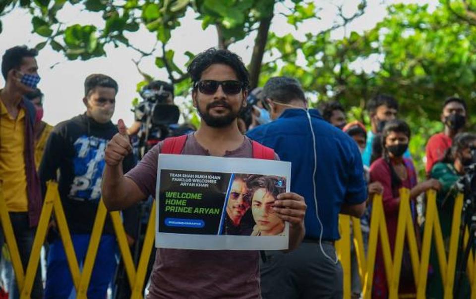 File photo: Fans stand with posters of Bollywood actor Shah Rukh Khan and his son Aryan Khan outside his residence on 29 October (AFP via Getty)