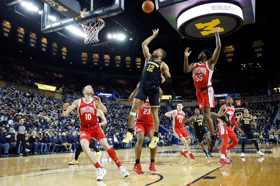 Michigan Wolverines guard DeVante' Jones (12) shoots the ball against Ohio State Buckeyes forward Zed Key (23) and forward Justin Ahrens (10) in the first half at Crisler Center.