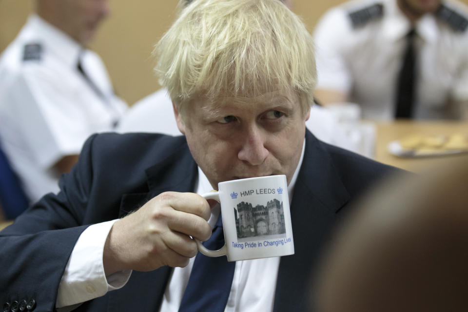 Britain's Prime Minister Boris Johnson takes a drink from a prison mug as he talks with prison staff during a visit to Leeds prison, Northern England, Tuesday Aug. 13, 2019. In an announcement on Sunday Johnson promised more prisons and stronger police powers in an effort to fight violent crime. ( AP Photo/Jon Super)