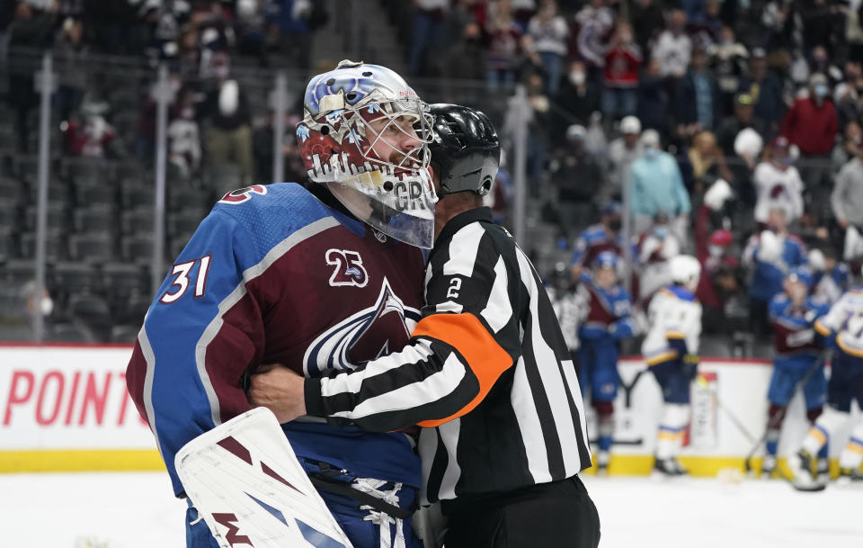 Referee Mike Hasenfratz, right, holds back Colorado Avalanche goaltender Philipp Grubauer as he exchanges words with St. Louis Blues goaltender Jordan Binnington after he skated down the ice to face Grubauer while he tangled with St. Louis Blues left wing Kyle Clifford as time ran out in Game 1 of an NHL hockey Stanley Cup first-round playoff series Monday, May 17, 2021, in Denver. Colorado won 4-1. (AP Photo/David Zalubowski)