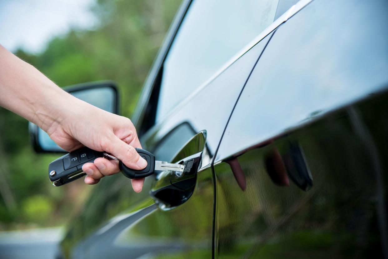 Woman hand inserting key in car door.