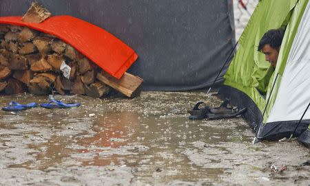 A refugee looks on as he sits inside his tent during heavy rainfall at a makeshift camp for migrants and refugees at the Greek-Macedonian border near the village of Idomeni, Greece, May 21, 2016. REUTERS/Kostas Tsironis