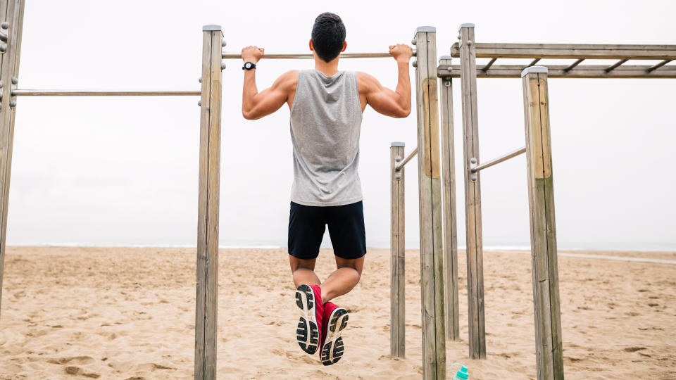 Man performing a pull-up on a beach