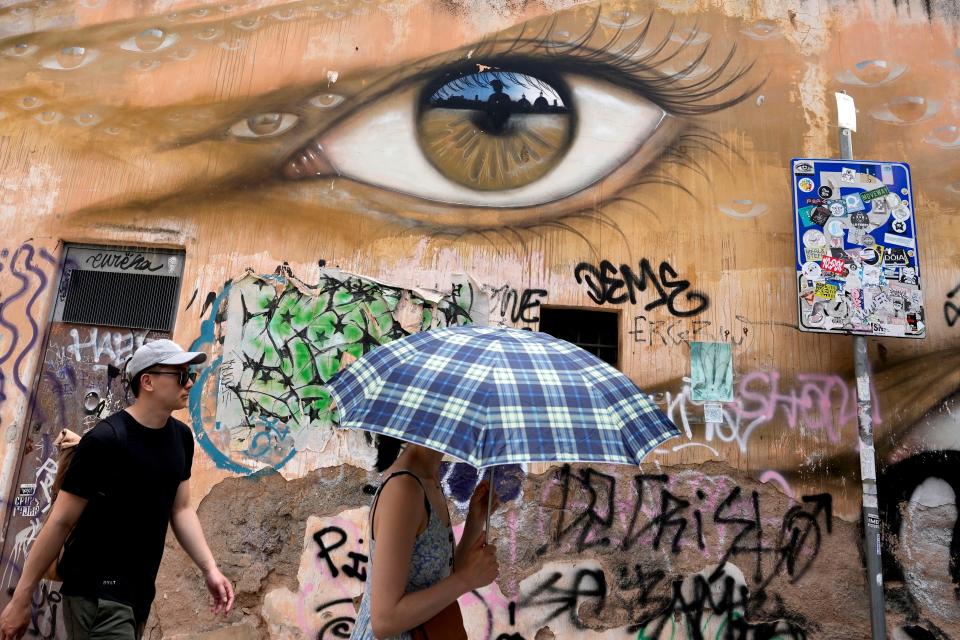 A woman uses an umbrella to take shelter from the sun as she walks in downtown Rome (AP)