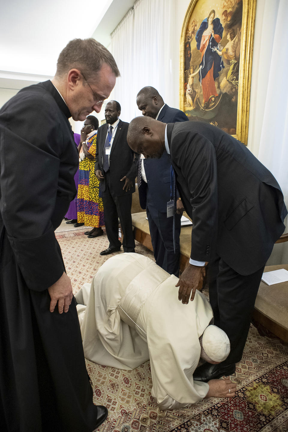 Pope Francis kneels to kiss the feet of South Sudan's Deputy President Taban Deng Gai, at the Vatican, Thursday, April 11, 2019. Pope Francis has closed a two-day retreat with South Sudan authorities at the Vatican with an unprecedented act of respect, kneeling down and kissing the feet of the African leaders. (Vatican Media via AP)