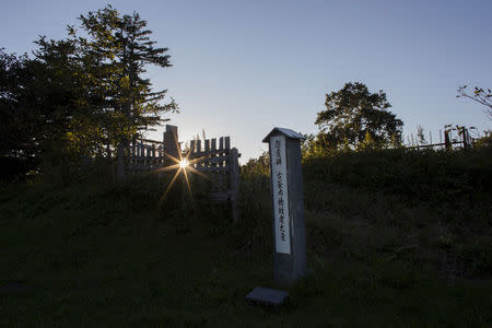 The evening sun breaks through a fence behind a recently erected tomb stone at a historic Japanese cemetery in Yuzhno-Kurilsk, the main settlement on the Southern Kurile Island of Kunashir September 14, 2015. REUTERS/Thomas Peter/File Photo