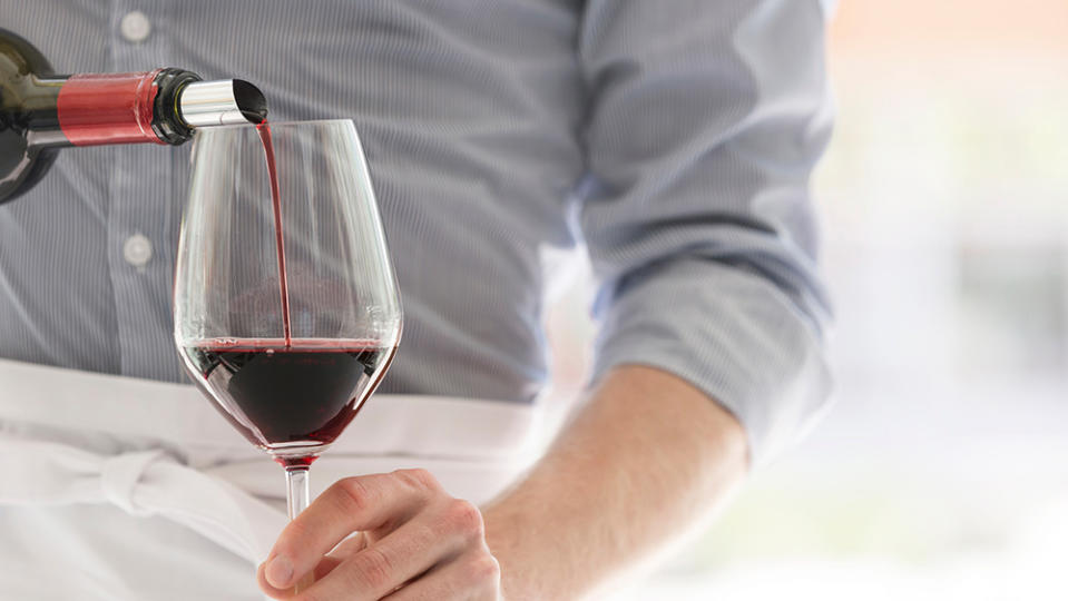 Midsection of waiter pouring red wine in wineglass at restaurant; Shutterstock ID 1413677858; Notes: Robb Report—Waiters (pg 81)