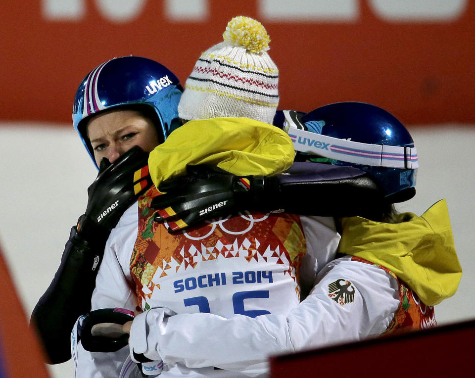 Germany's Carina Vogt, left, is hugged by teammates after winning the gold during the women's normal hill ski jumping final at the 2014 Winter Olympics, Tuesday, Feb. 11, 2014, in Krasnaya Polyana, Russia. (AP Photo/Charlie Riedel)