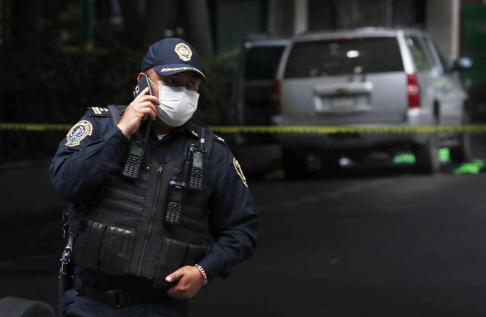 An abandoned vehicle that is believed to have been used by gunmen in an attack against the chief of police is sealed off with yellow tape and guarded by police, in Mexico City, Friday, June 26, 2020. Heavily armed gunmen attacked and wounded Omar Garcia Harfuch in a brazen operation that left an unspecified number of dead, Mayor Claudia Sheinbaum said Friday. (AP Photo/Marco Ugarte)