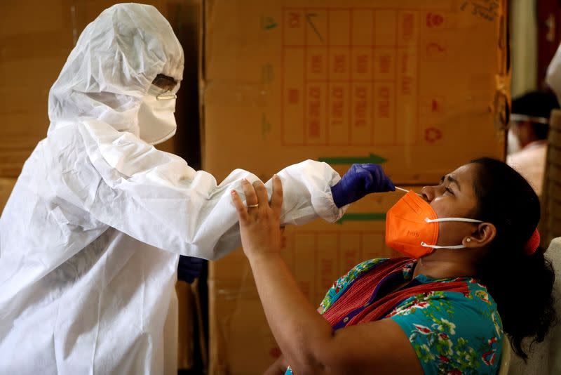 FILE PHOTO: A health worker in personal protective equipment (PPE) collects a swab sample from a woman during a rapid antigen testing campaign for the coronavirus disease (COVID-19), in Mumbai