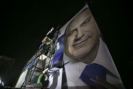 Workers install a campaign poster of Israel's Prime Minister Benjamin Netanyahu on a billboard in Tel Aviv March 10, 2015. REUTERS/Baz Ratner