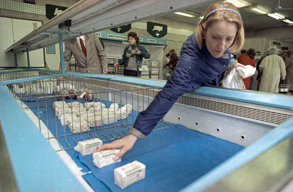 FILE - A Soviet woman reaches for one of the last packs of butter from a nearly empty refrigerator in a local shop in Moscow on June 1, 1990. Food shortages, always a common occurrence in the Soviet Union, have become worse recently. Over the next four months, the USSR disintegrated with the slow drama of a calving glacier. (AP Photo/Alexander Zemlianichenko, File)