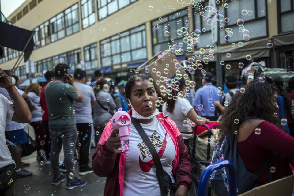 A street vendor sells a device that makes bubbles at the Mesa Redonda Market, a popular spot for Christmas shopping, amid the COVID-19 pandemic in Lima, Peru, Monday, Dec. 21, 2020. (AP Photo/Rodrigo Abd)