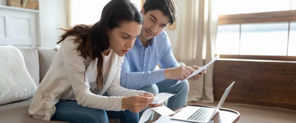 Concentrated attentive millennial couple sitting at home office in living room shopping for mortgage rates and ready to apply for a refinance loan.