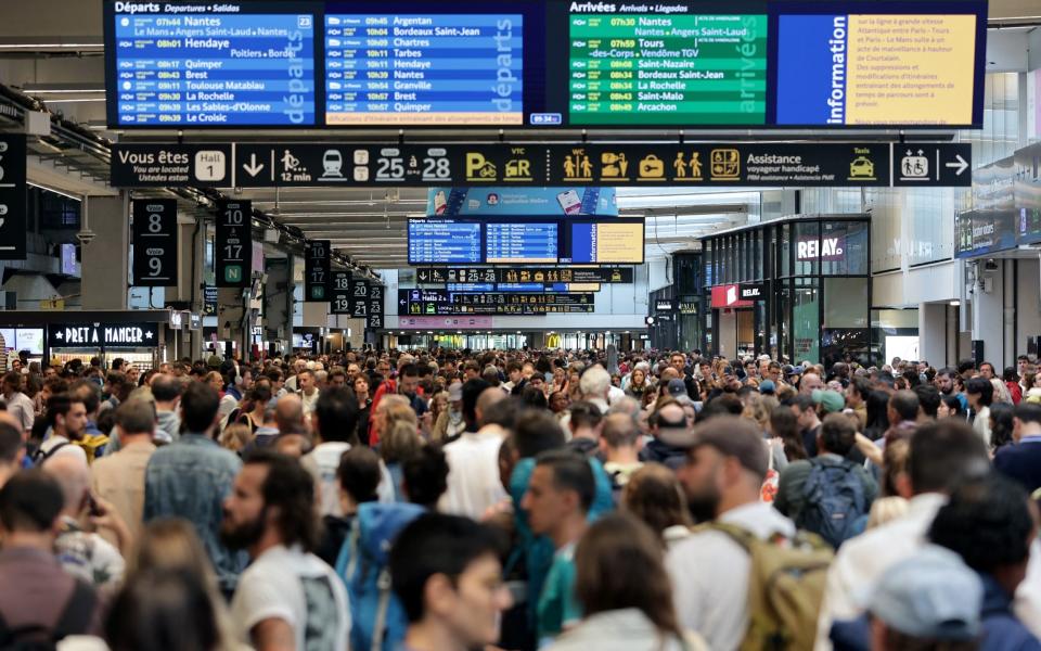 Passengers gather around the departure boards at the Gare Montparnasse train station in Paris