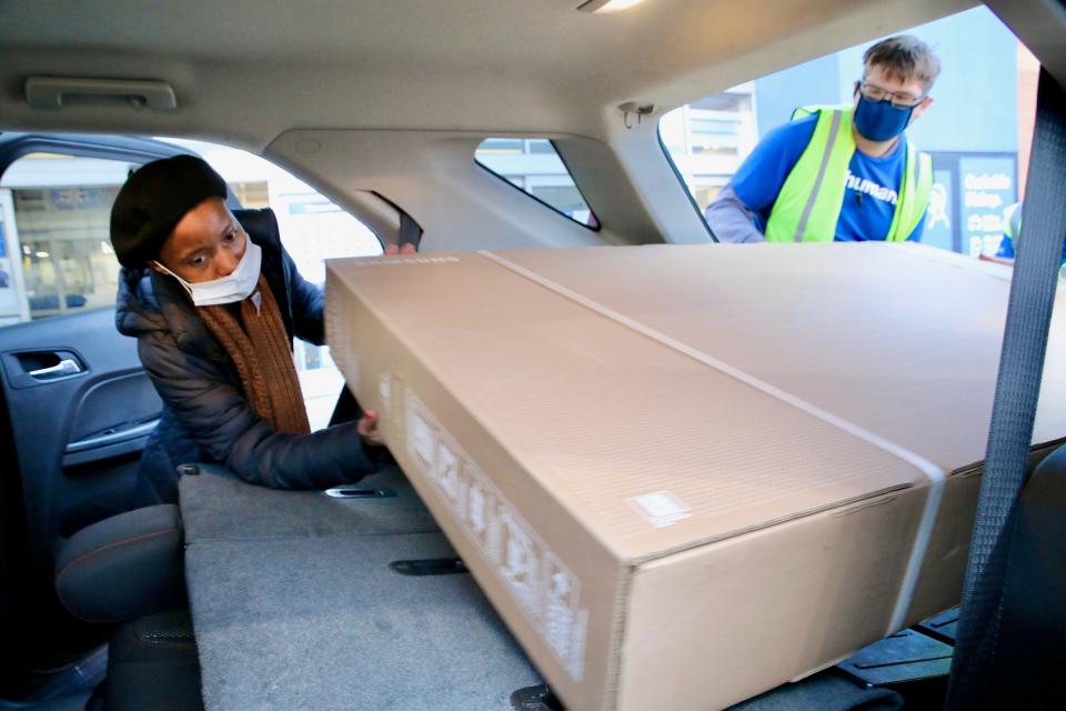 Jenise Palmer and a Best Buy employee load a new 70-inch television inside her car Friday, Nov. 26, 2021. Palmer was one of many Black Friday shoppers to hit the stores Friday looking for deals.