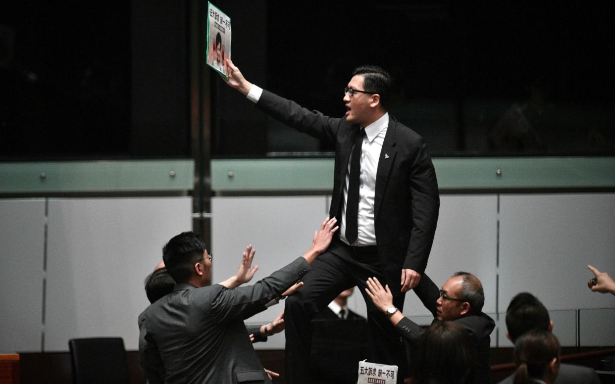 Pro-democracy lawmaker Lam Cheuk-ting stands up and protests shortly before Hong Kong's Chief Executive Carrie Lam leaves the chamber for the second time while trying to present her annual policy address last year - AFP