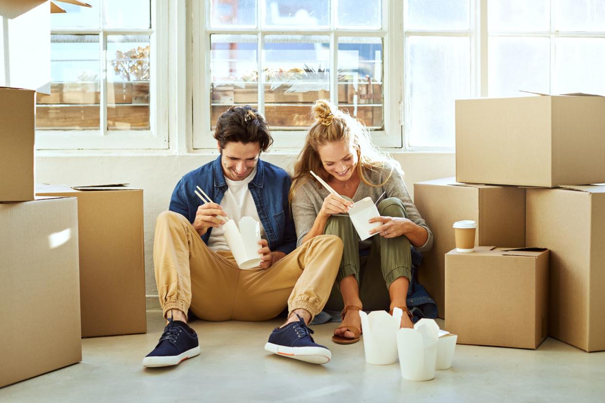 Shot of a young couple eating takeout while taking a break moving into their new home