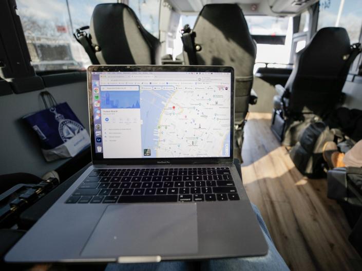 A laptop with a map of Manhattan. Bus seats and large windows are behind it.